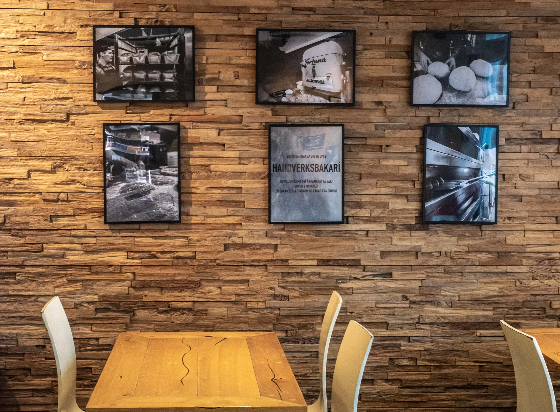 Inside Reynir bakari on Dalvegur: a wall of framed black-and-white bakery photographs above the tables